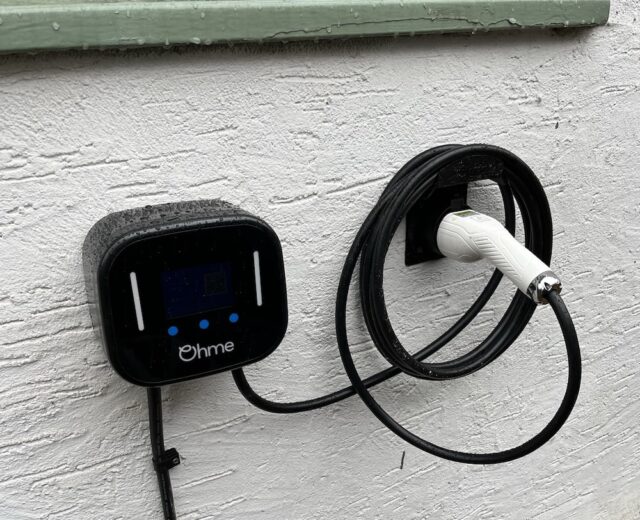image of Ohme Home Pro installed neatly on a white wall under a green window sill